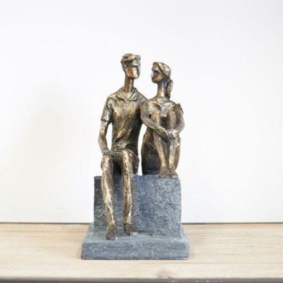 A resin couple statue, a couple in love statue featuring two bronze figures sitting on blocks