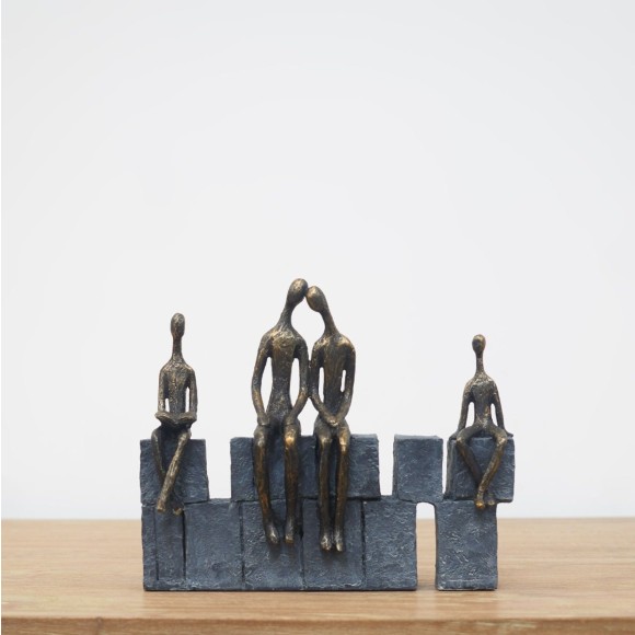 A resin family of 4 sculpture featuring parents and children sitting on blocks 