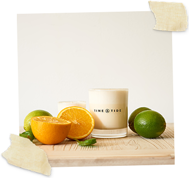 scented jar candle next to cut limes and orange