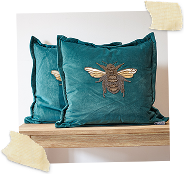 two teal velvet cushions with beaded bee motif to middle
