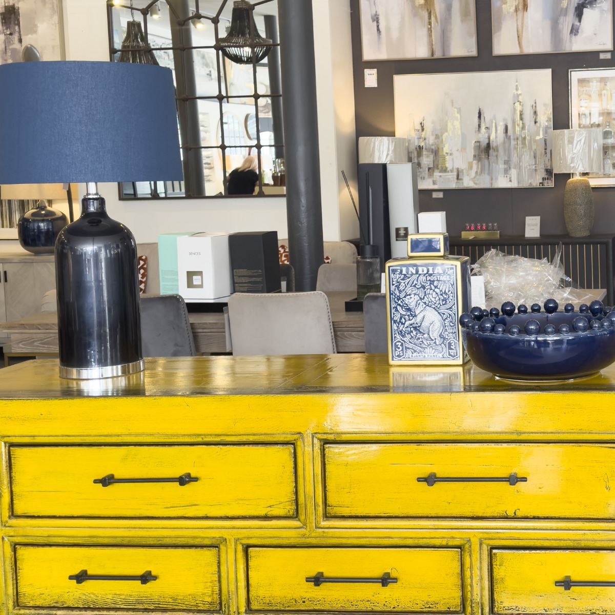 distressed yellow wood and metal sideboard with glossy ceramic navy bobble bowl, decorative ceramic lidded jar and navy glass table lamp
