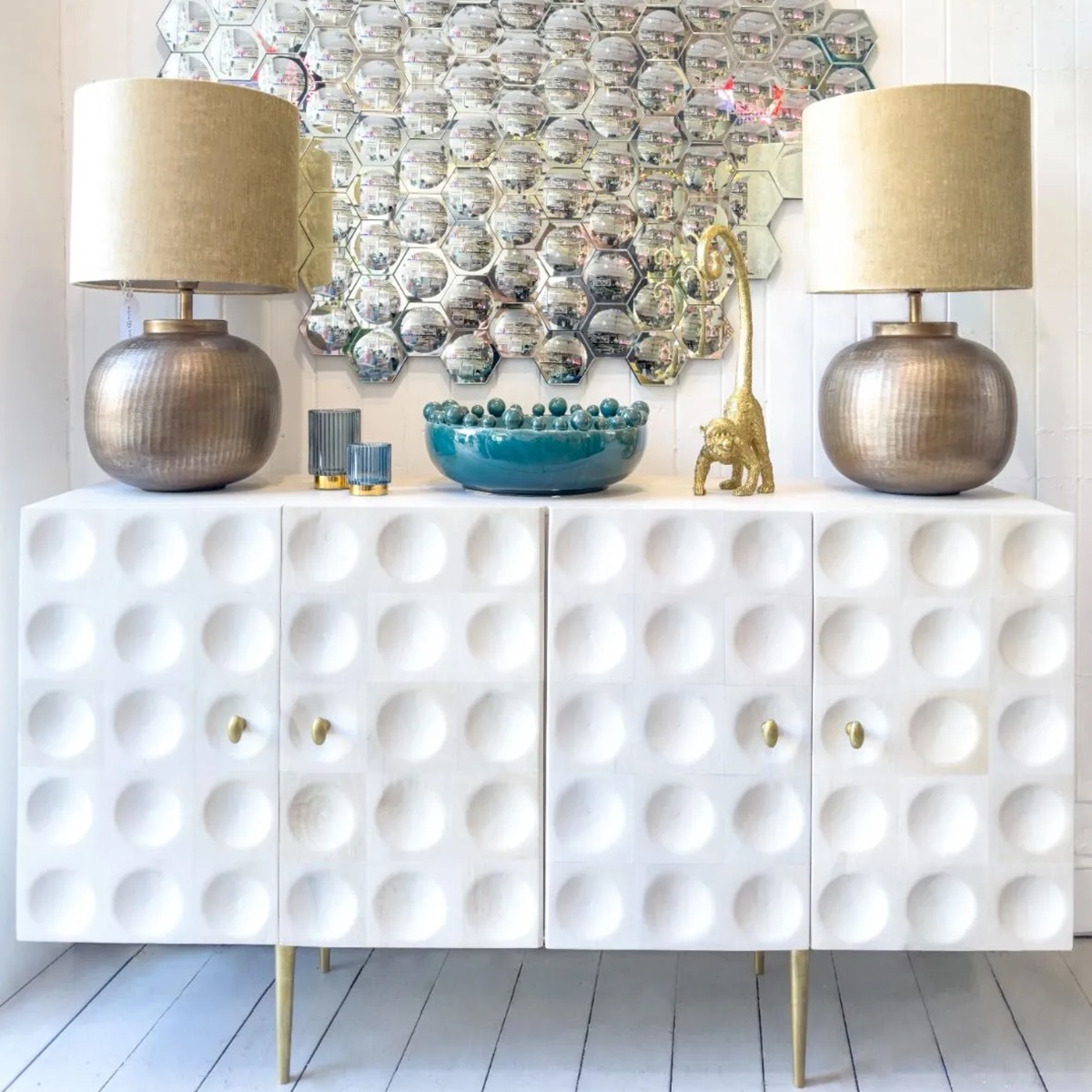 white wash dimpled mango wood sideboard with gold metal legs and handles, accessorised with a teal glossy ceramic bobble bowl and a gold decorative monkey scuplture