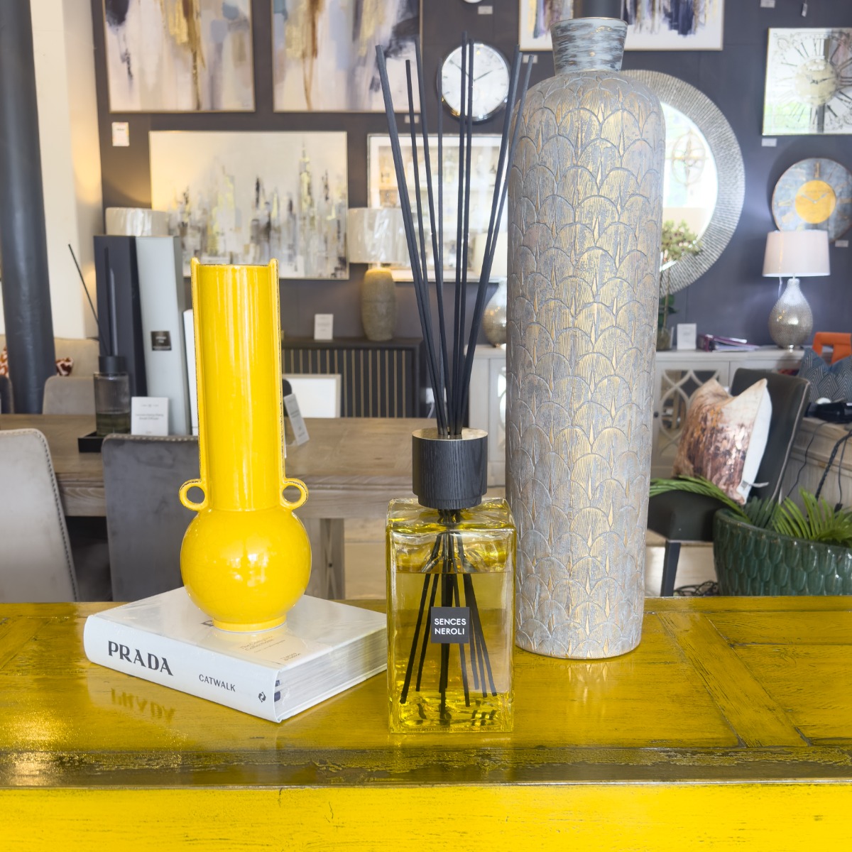 yellow painted wood sideboard with tall mustard ceramic vase, luxury glass reed diffuser and fashion coffee table book