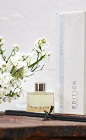 reed diffuser and box with white flowers on a wooden table top