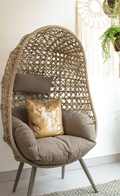 woven egg chair with legs with a gold cushion 