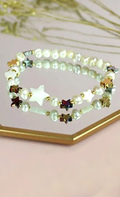 bracelet with white beads and gold stars on a mirrored tray
