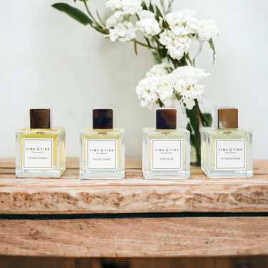 Four luxury perfumes on a wooden plinth with white hydrangeas in background