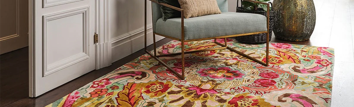 colourful floral rug in pinks, creams and greens on wooden floor with occasional chair