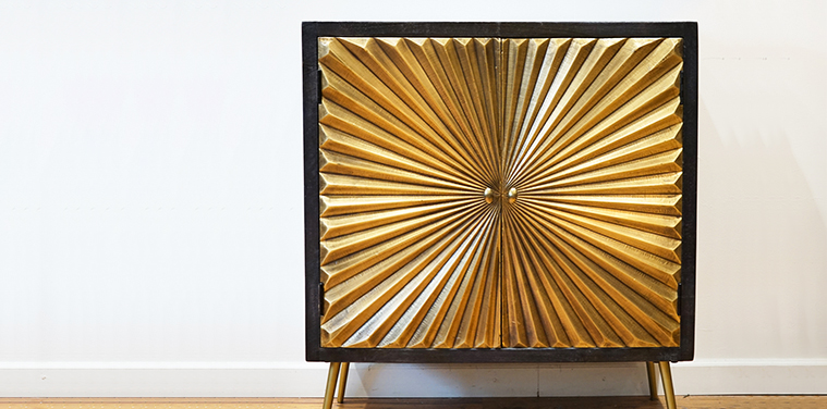 a gold starburst design two door cabinet on gold legs