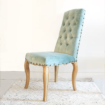 a green velvet dining chair with buttoned back