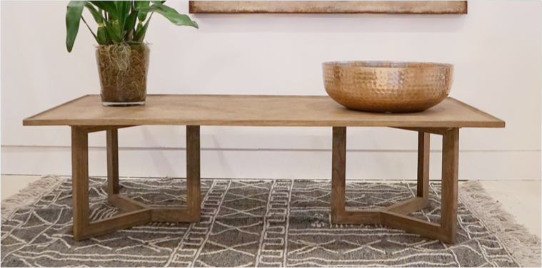 square wood coffee table on rug with plant and bowl