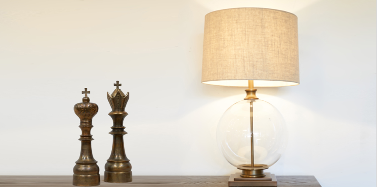bronze glass ball lamp with linen drum shade on console next to chess piece sculptures