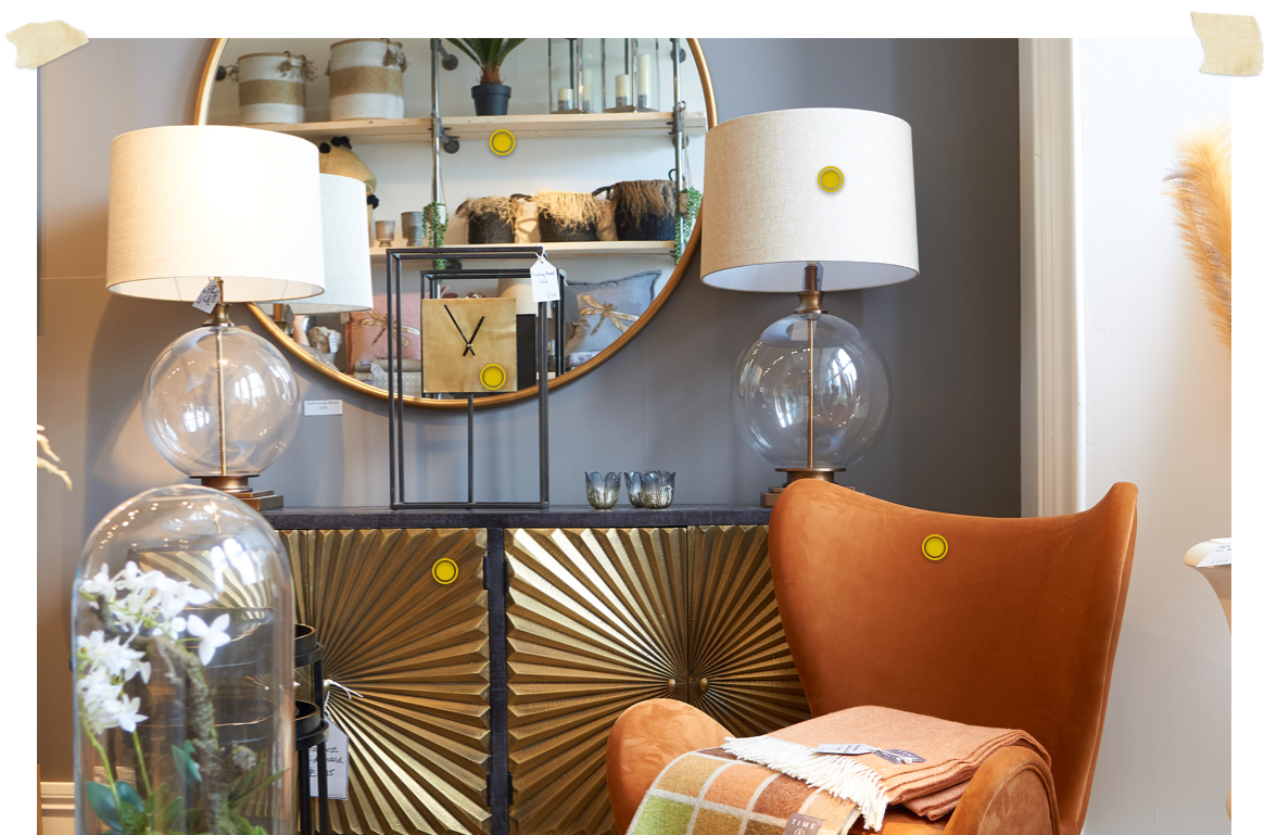 gold starburst sideboard with lamps and clock on top with mirror hung on grey wall and orange wing chair