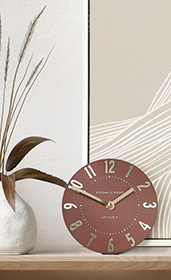 grey wall clock hung on wall above sideboard with books 