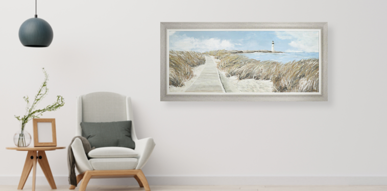 wall art print depicting coastal scene hung on wall next to chair and side table