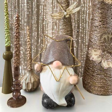 a collection of christmas decorations including an elf with led star and tree shaped candlesticks sitting on a wooden table